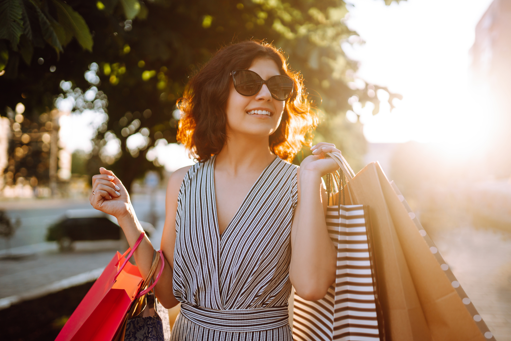 Young woman after shopping with shopping bags walking on street. The joy of consumption. Consumerism, sale, purchases, shopping, lifestyle concept.